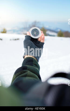 Man holding a metal compass on snowy mountain Stock Photo