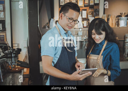 Two of asian baristas taking an order by digital tablet. Cafe restaurant service, food and drink industry concept. Stock Photo