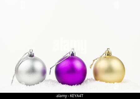 Golden, silver and purple Christmas balls with snow isolated on white background Stock Photo