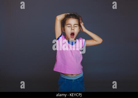 girl yawns wants to sleep on a gray background Stock Photo