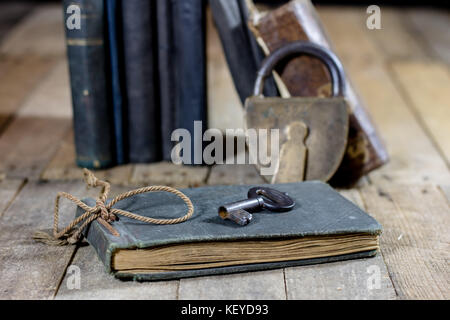 Very old book and key on an old wooden table. Old room, wooden table and book with key, black background Stock Photo