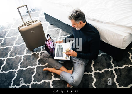 Unrecognizable businessman with laptop in a hotel room. Handsome man using online phone call and video. Stock Photo