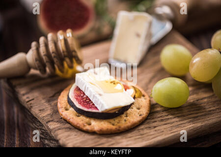 Cheese crackers with camembert and fresh fig and honey. Stock Photo