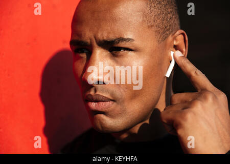 Close up portrait of a concentrated young african man with earphones looking away Stock Photo