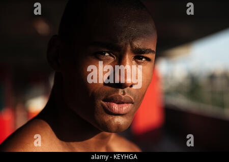 Close up portrait of a young focused african sportsman looking at camera indoors Stock Photo