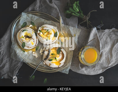 Merengues with lemon curd, fresh mint on silver tray, beige kitchen towel Stock Photo