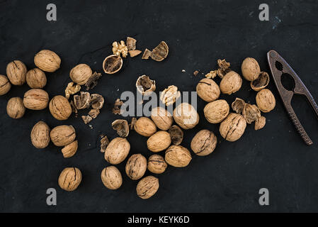 Walnuts with nutcracker over black slate stone background Stock Photo