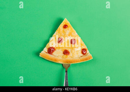 Slice of pizza on a fork on a green background Stock Photo