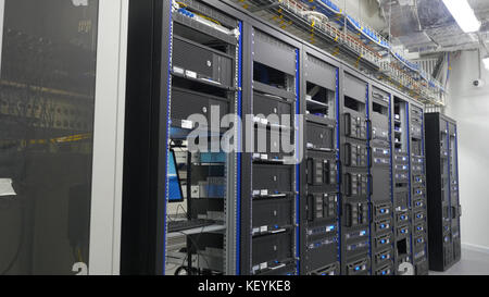 Many powerful servers running in the data center server room. Many servers in a data center. Many racks with servers located in the server room. Bright display a plurality of operating equipment. Stock Photo