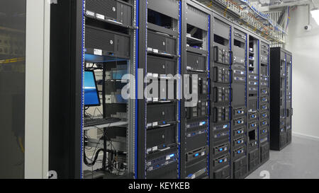 Many powerful servers running in the data center server room. Many servers in a data center. Many racks with servers located in the server room. Bright display a plurality of operating equipment. Stock Photo