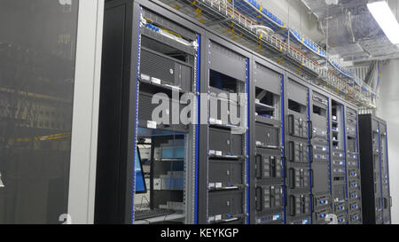 Storage servers are located in the server room of the data center. Back of the server installed in the server room. Many cables are connected to a powerful computers Stock Photo
