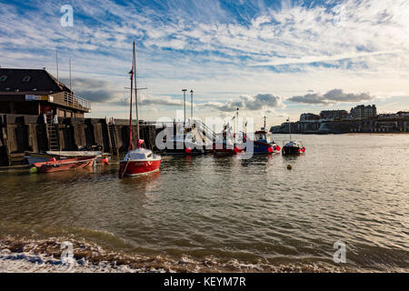 A red yacht and small trawlers in the harbour at Broadstairs, Kent, Uk, as the sun begins to set. Stock Photo