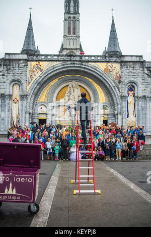 photographer taking pictures of group photo of tourists in front of the cathedral in Lourdes, France, Europe.