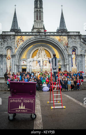 photographer taking pictures of group photo of tourists in front of the cathedral in Lourdes, France, Europe.