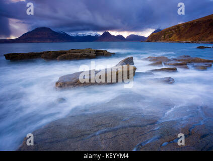 Sunset on the Isle Of Skye looking out over Loch Scavaig to the Cullin Ridge. Long exposure to blur the water with clouds lit by the setting sun Stock Photo