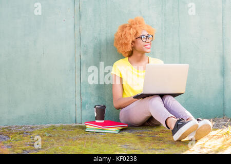African woman with laptop on the green background Stock Photo