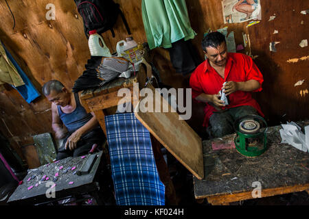 Salvadoran shoemakers work on new shoes, attaching both insoles and outsoles, in a shoe making workshop in San Salvador, El Salvador, 16 November 2016 Stock Photo