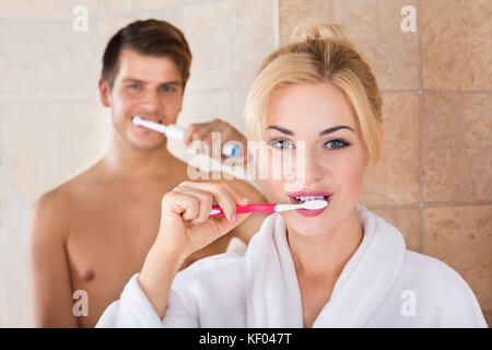 Portrait Of Man And Woman Brushing Teeth In Bathroom At Home Stock Photo