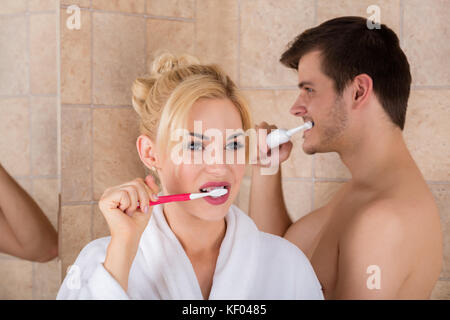 Portrait Of Man And Woman Brushing Teeth In Bathroom At Home Stock Photo