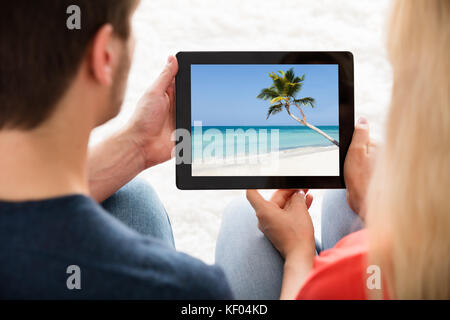 Close-up Of Young Couple Sitting Looking At Photo On Digital Tablet At Home Stock Photo