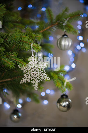 Antique style silver baubles, snowflake on real Christmas tree Stock Photo