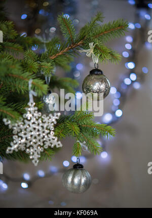 Antique style silver baubles, snowflake on real Christmas tree Stock Photo