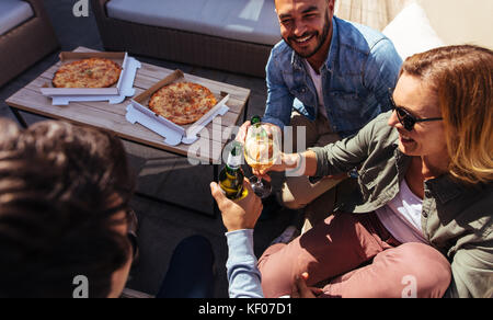 Young people clinking drinks during party on rooftop. Group of millennial having drinks at outdoor party. Stock Photo