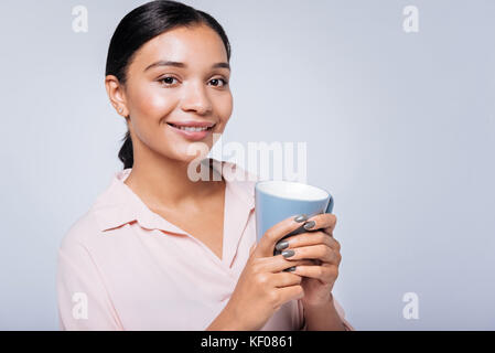 Pleasant smiling woman posing with a blue cup of coffee Stock Photo
