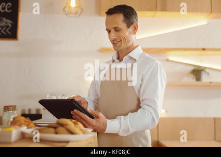 Cheerful happy cook using modern technology Stock Photo