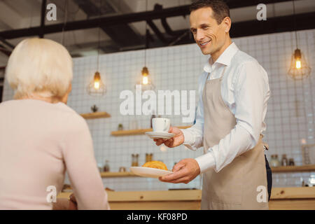 Joyful positive waiter serving breakfast Stock Photo