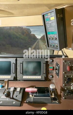 Interior view of the drivers cab inside train with a large window with a view of the tracks and several panels with levers and buttons Stock Photo