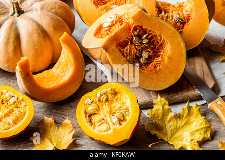 Sliced pumpkin with seeds on a wooden background. Close-up Stock Photo