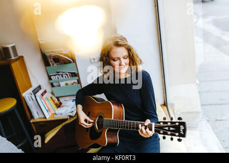 portrait of young blonde female singer plucking a guitar Stock Photo