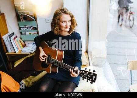 portrait of young blonde female singer plucking a guitar Stock Photo