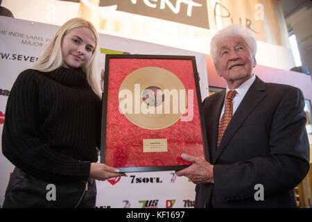 Stuttgart, Germany. 24th Oct, 2017. Choir director Gotthilf Fischer holding a golden record in his hands next to the 15-year old new-coming artist Jellina Hauser in Stuttgart, Germany, 24 October 2017. For 7 decades Gotthilf Fischer has been bringing choir music to Germany's turntables. His music label awarded the composer and director of the Fischer Choir with a golden record for '70 years of recording'. Credit: Marijan Murat/dpa/Alamy Live News Stock Photo