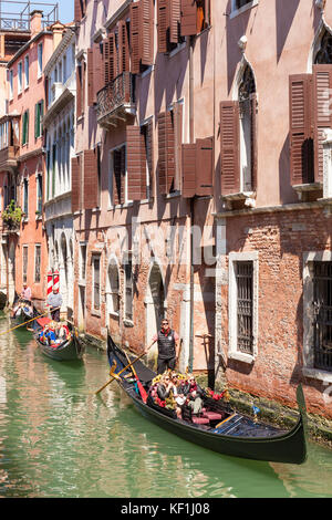 VENICE ITALY VENICE many gondolas carrying tourists travelling down in a small canal in Venice Italy eu europe Stock Photo