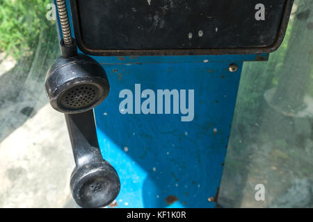 Hanging old phone receiver in old phone booth Stock Photo
