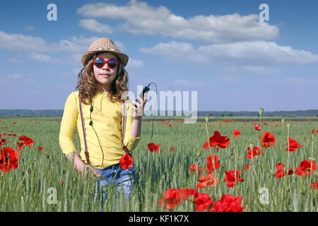 little girl listening music on phone in meadow Stock Photo