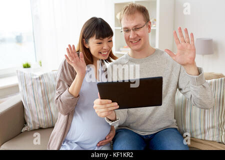 husband and pregnant wife with tablet pc at home Stock Photo