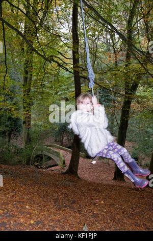 Sheffield, UK - Jan 2015: Young girl plays on rope swing in Glen Howe park woodland on 18 Jan 2015, near Wharncliffe Side Stock Photo
