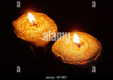 Close up of two lit gold candles on black background Stock Photo