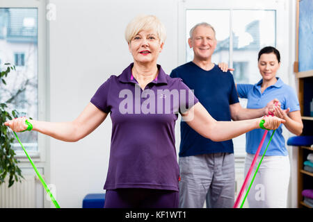 Older patients in physiotherapy using power band for strength tr Stock Photo