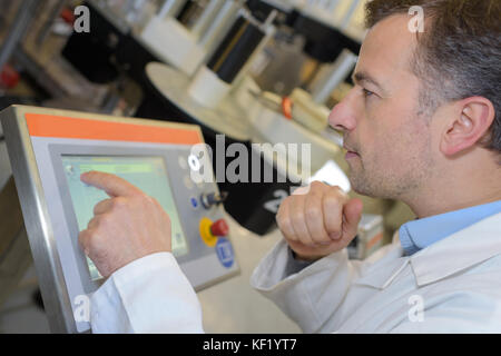 worker operating a machine with a control panel Stock Photo