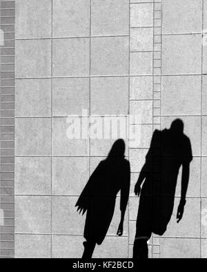 Shadow of a woman and a man, on city sidewalk from above in black and white Stock Photo