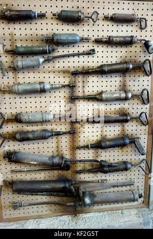 A display of antique grease guns on a wall Stock Photo