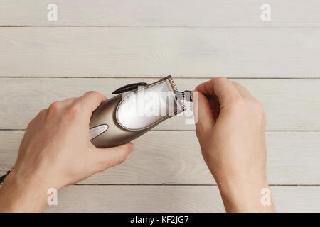 Man Hand holding hair clippers on white wooden background Stock Photo