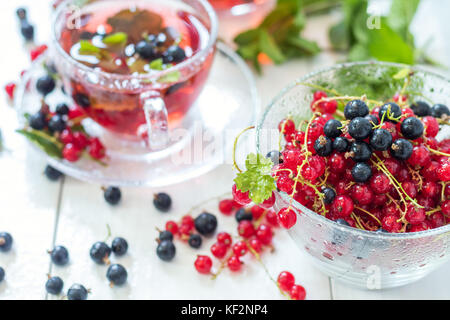 Fresh juicy red and black currant with dew drops in clear glass vase on the table. Shallow depth of field Stock Photo