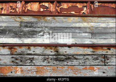 Peeled paint, worn nails and rust on weathered old wooden ship hull boards at Siglufjordur shipyard dock, North Iceland