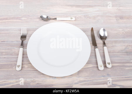 empty plate with knife and fork on empty retro vintage wooden table. Stock Photo