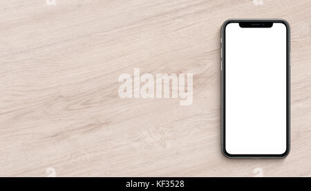 Smartphone similar to iPhone X mockup flat lay top view lying on wooden office desk. Banner with copy space. Stock Photo